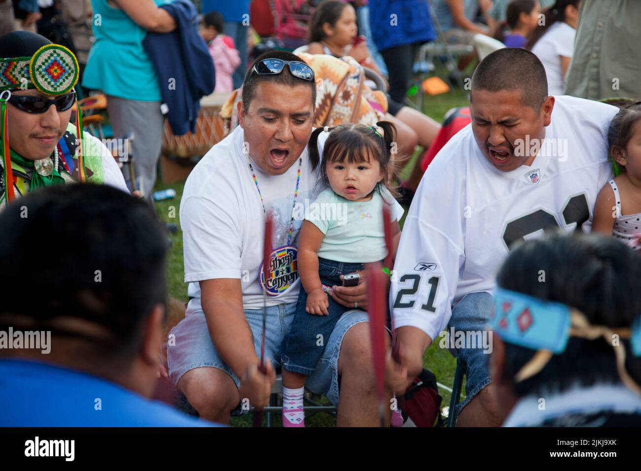 I batteristi di Pow Wow tengono i bambini mentre suonano una canzone tradizionale allo Shoshone Bannock Pow Wow, Fort Hall, Idaho Foto Stock