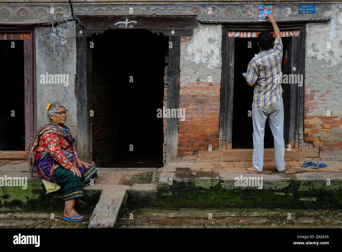 Bhaktapur, Nepal. 02nd ago 2022. Il 2 agosto 2022 a Bhaktapur, Nepal. Un uomo adora la divinità serpente (serpente) al passo della porta principale della casa durante il Nag Panchami Festival. La gente in questo giorno attacca il manifesto della divinità serpente (serpente) sul gradino principale della porta della casa, stagno locale pulito più vicino e adorano gli dei serpenti, anche chiamato il Nagas durante Nag Panchami. NAG Panchami Festival cade il mese di Shrawan accourding al calendario nepalese o luglio/agosto. (Foto di Abhishek Maharjan/Sipa USA) Credit: Sipa USA/Alamy Live News Foto Stock