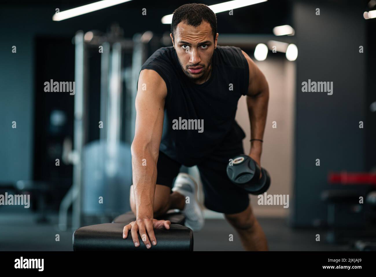 Muscoloso afroamericano che fa il bicipite allenamento con dumbbell in palestra Foto Stock