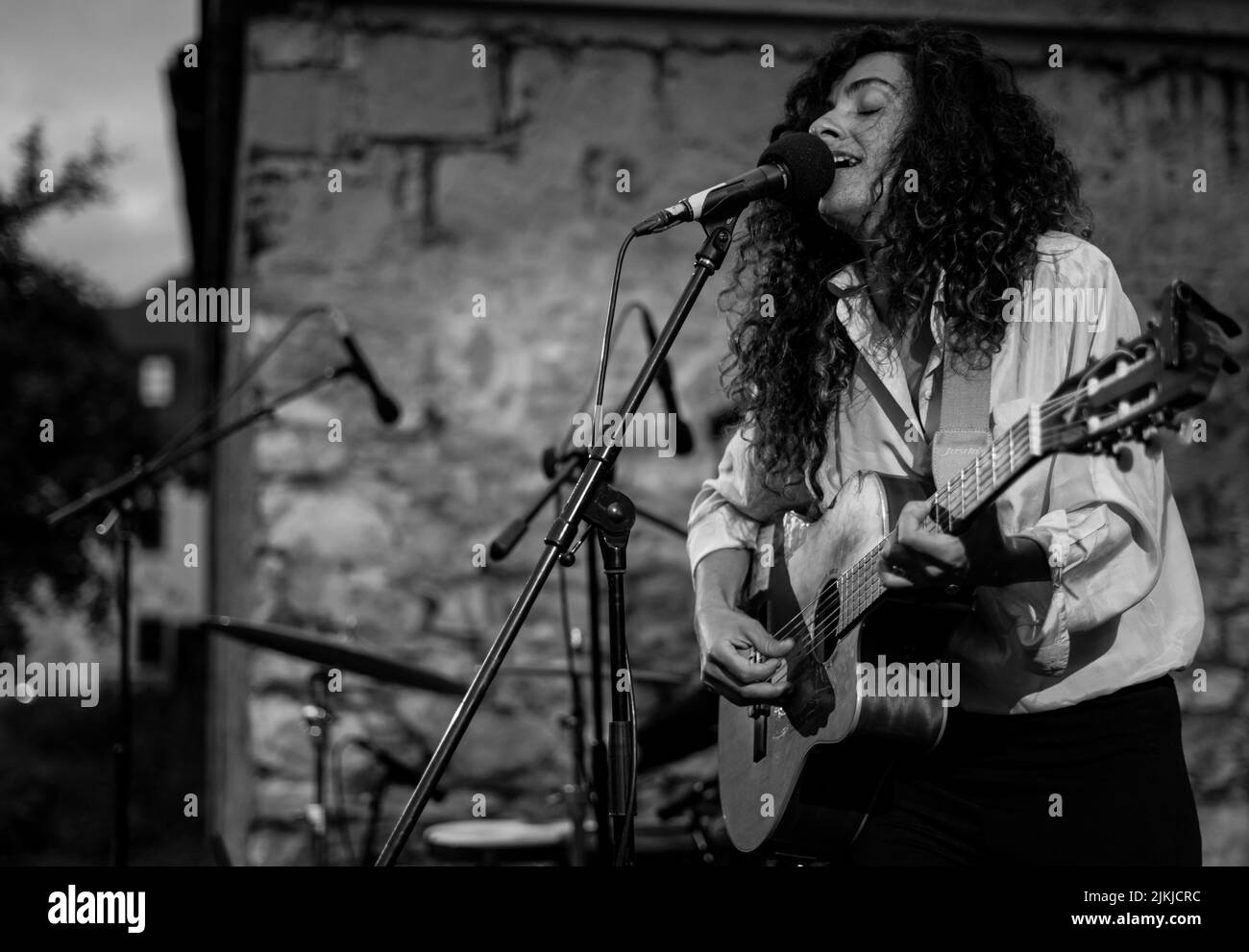 Giovane cantante femminile che canta e suona la chitarra in un Conc dal vivo Foto Stock