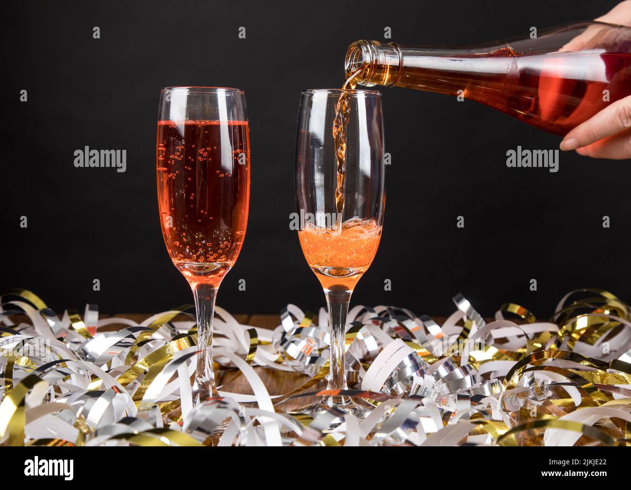 Un primo piano di bicchieri di champagne rosso con streamer alla festa di Capodanno Foto Stock