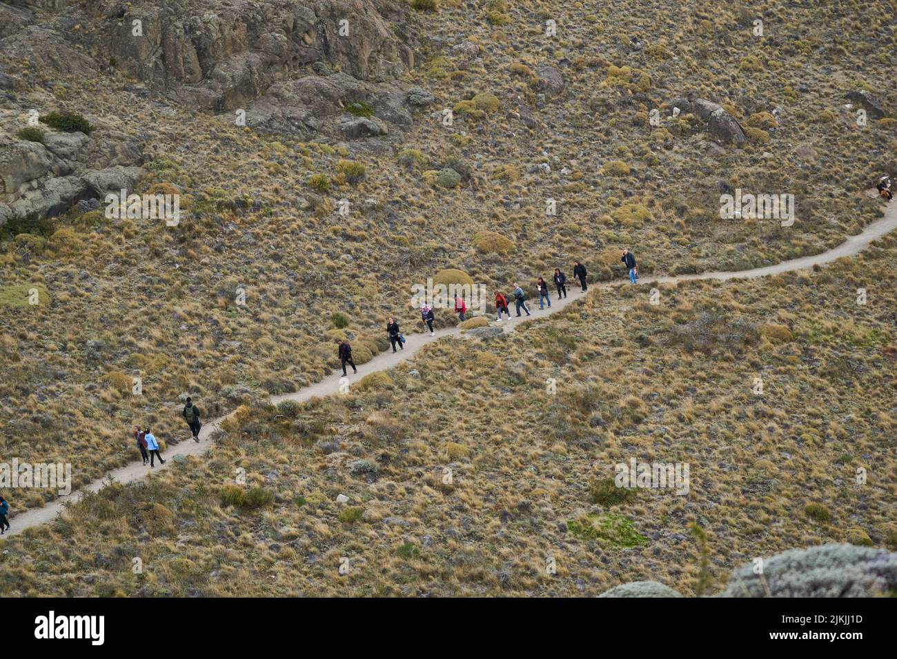 Un gruppo di escursionisti che camminano lungo uno stretto sentiero collinare Foto Stock
