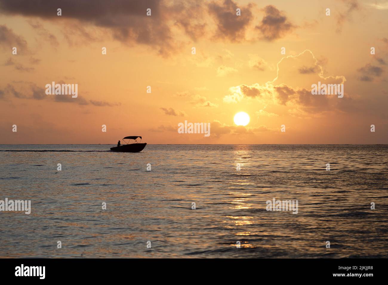 Una vista panoramica di una barca che naviga su un mare calmo durante il tramonto Foto Stock