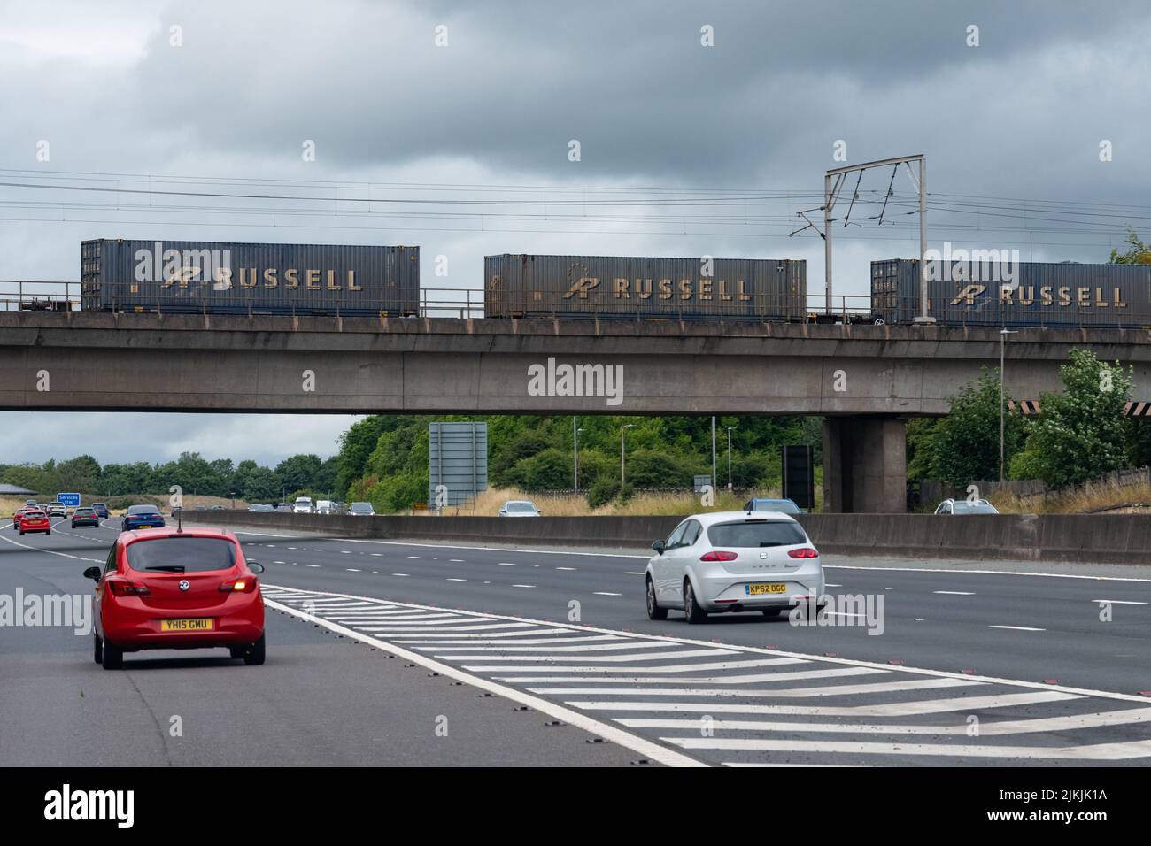 Russell logistica vagoni ferroviari merci che attraversano le automobili sull'autostrada M6, Scozia, Regno Unito Foto Stock
