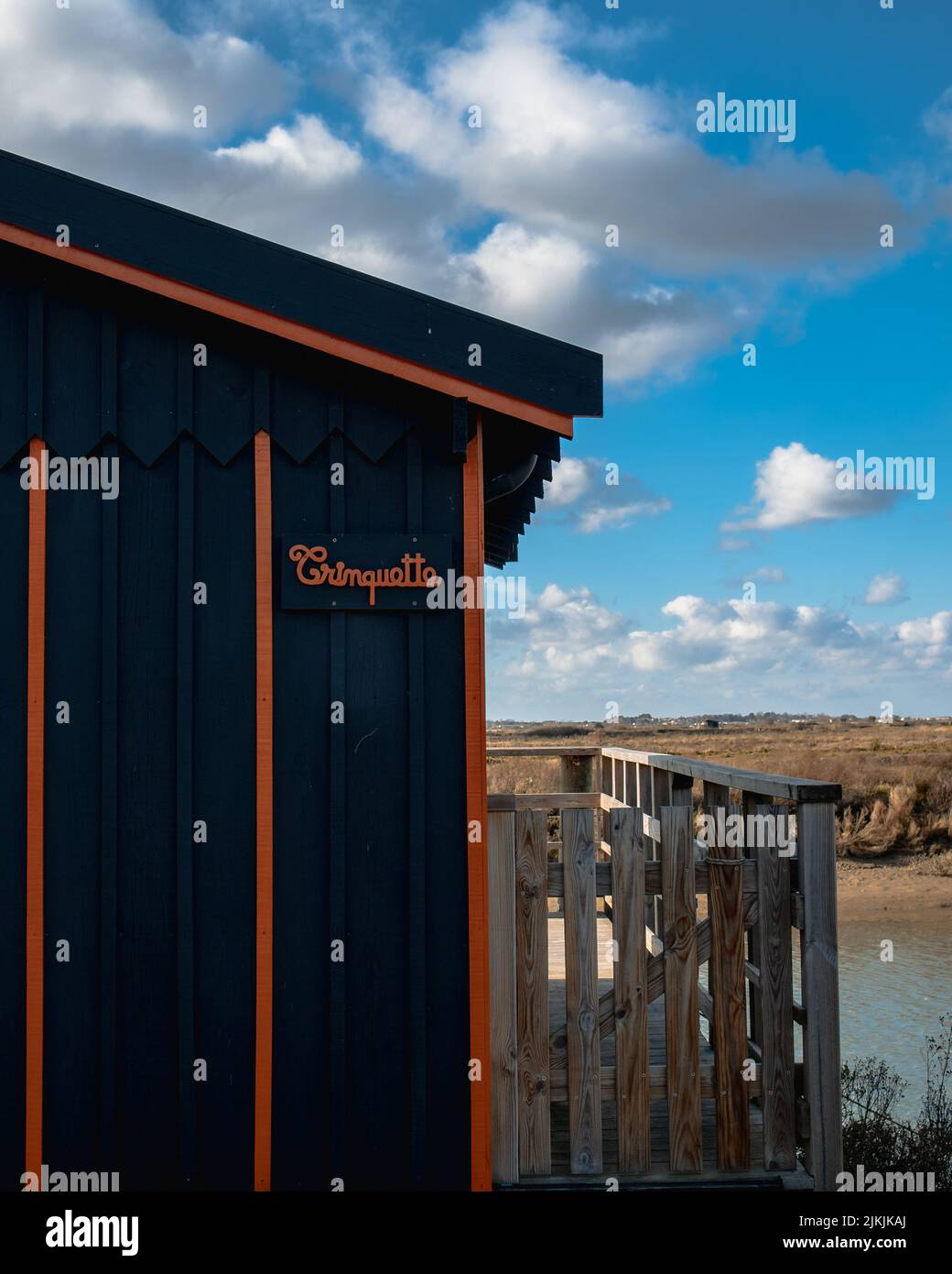 Uno scatto verticale di una parte di un edificio con un cartello sullo sfondo di un lago a Mornac sur Seudre, Francia. Foto Stock