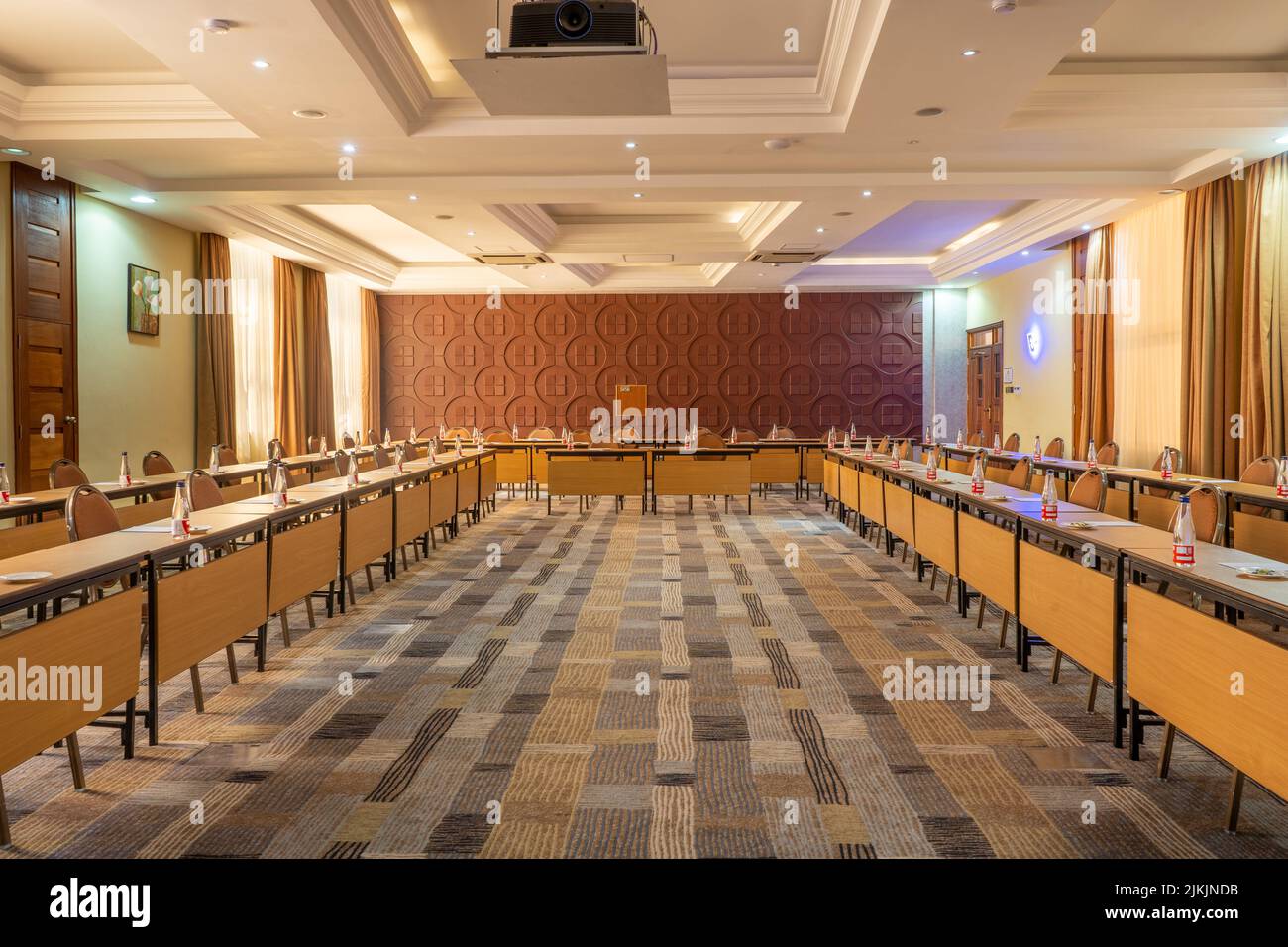 Una sala conferenze vuota con tavoli organizzati con bottiglie d'acqua Foto Stock