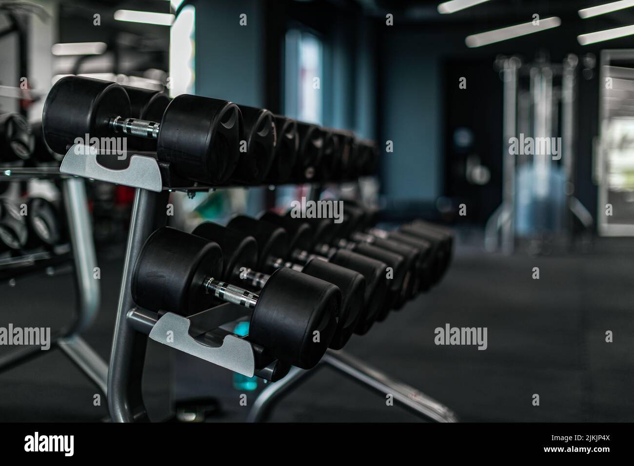 Concetto di attrezzatura sportiva. Set di manubri posti sul rack in palestra Foto Stock