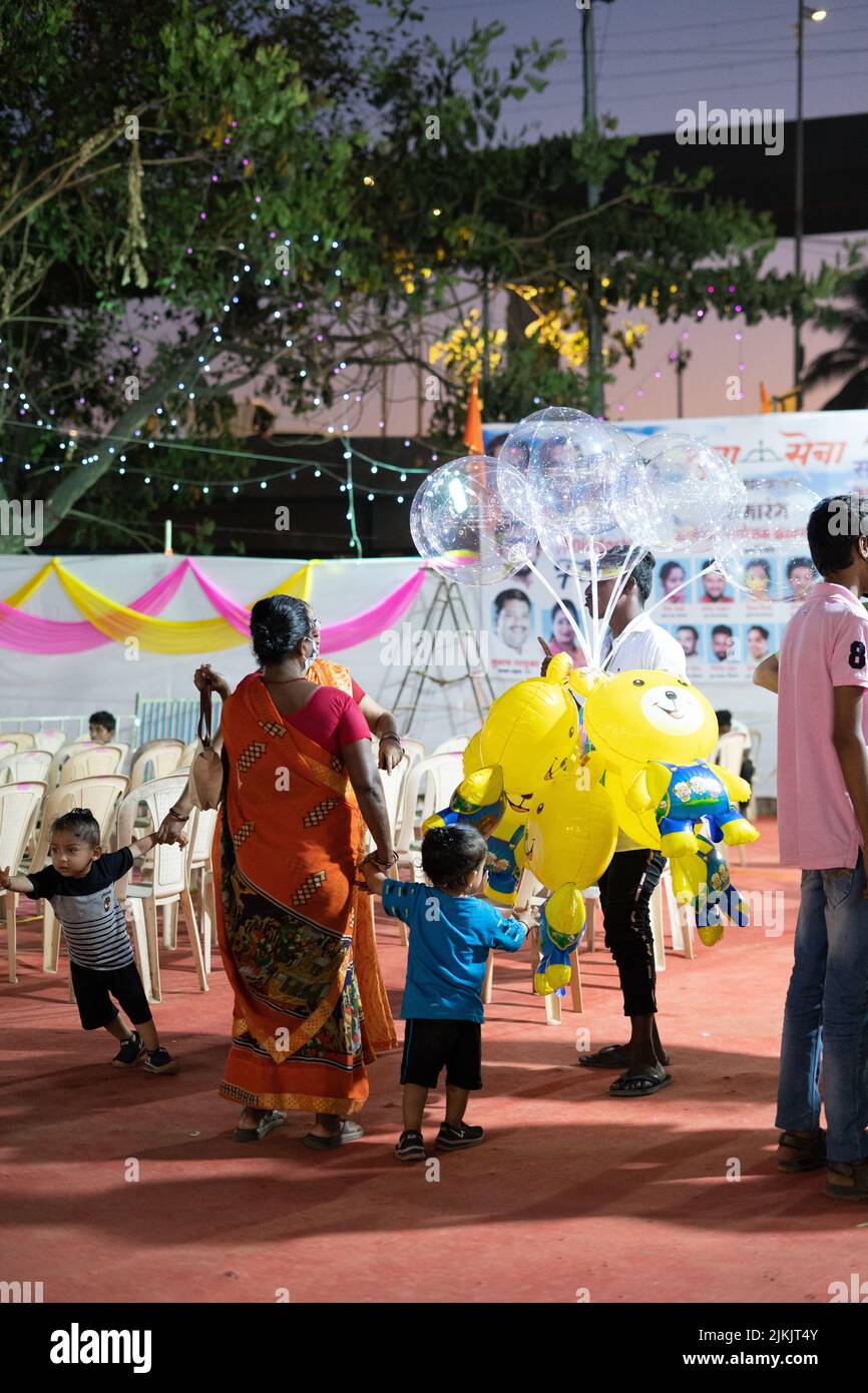 Una madre che acquista una mongolfiera in un festival di carnevale a Mumbai Foto Stock