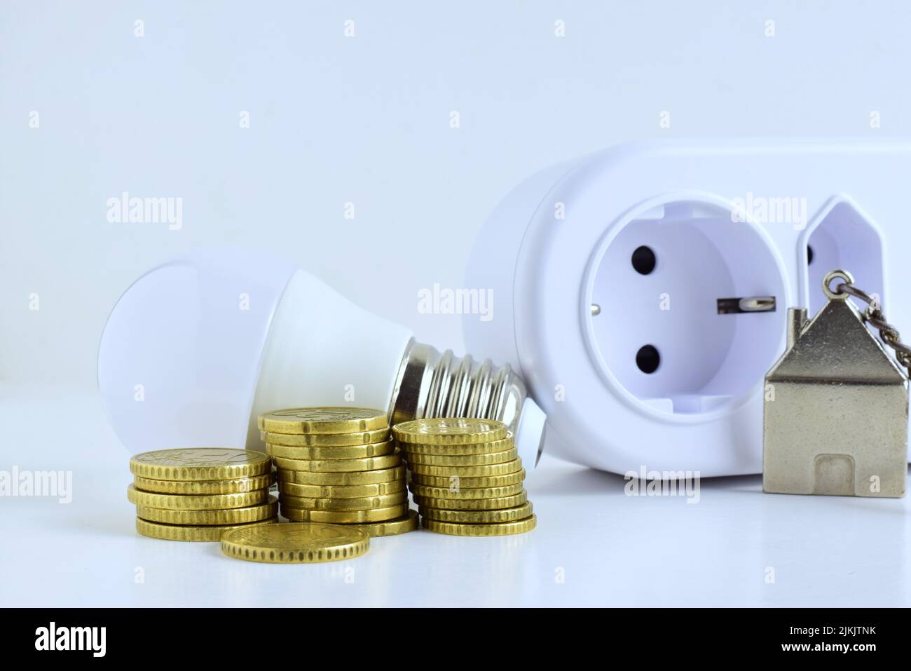 Un primo piano di monete, lampadina e una presa Foto Stock