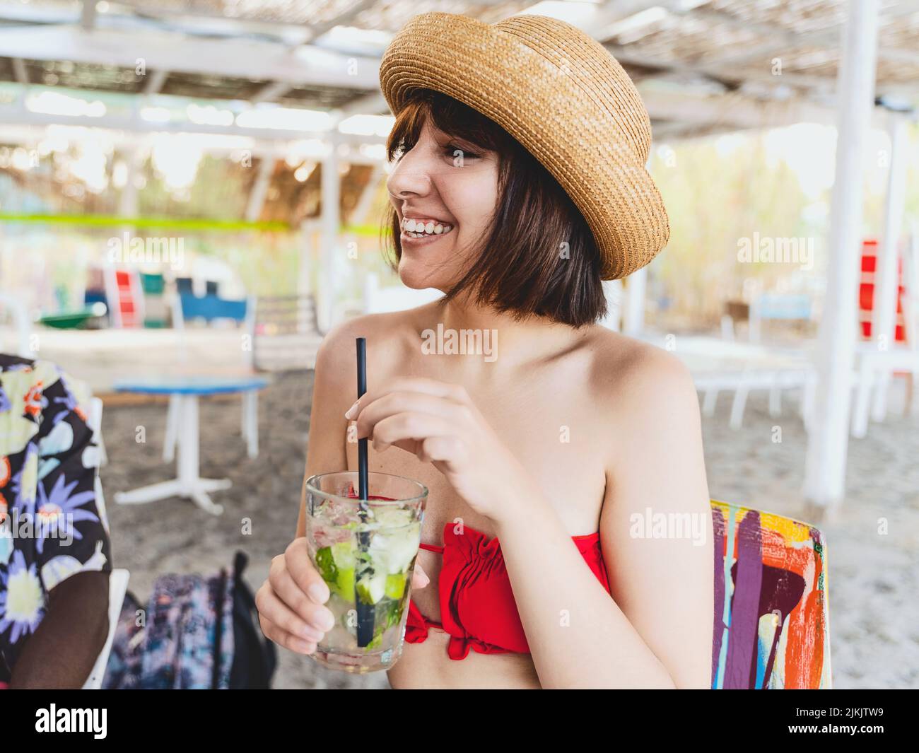 Bella giovane donna che parla con i suoi amici tenendo un bicchiere con una bevanda analcolica cocktail seduti al chiosco all'aperto cafe pub - alcol e persone su v Foto Stock