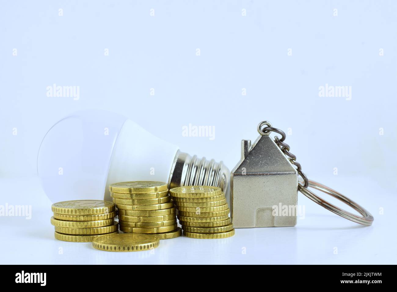 Le monete d'oro in euro accanto a un trinket casa e lampadina - concetto economico casa Foto Stock