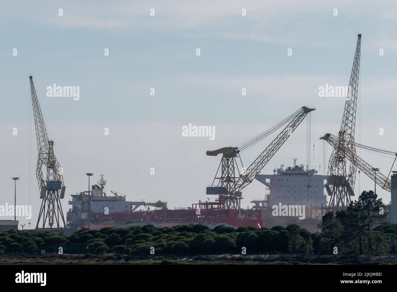 La società navale di Lisnave che ripara navi e gru da carico in background nel porto di Setubal, Portogallo Foto Stock