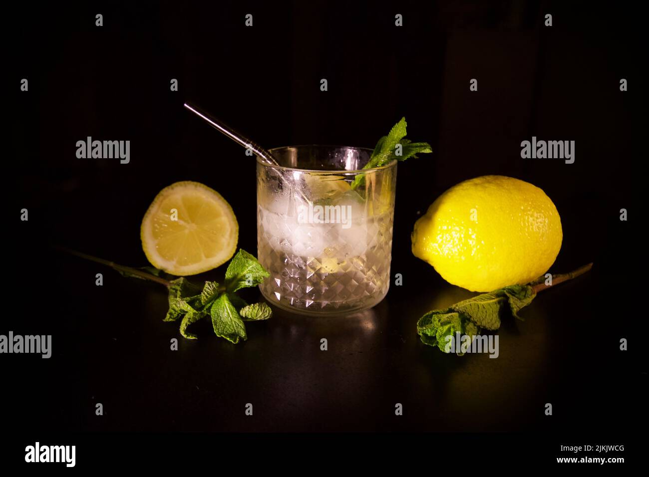Un primo piano di cocktail tonico alla menta al limone con limone e mezzo isolato su sfondo nero Foto Stock