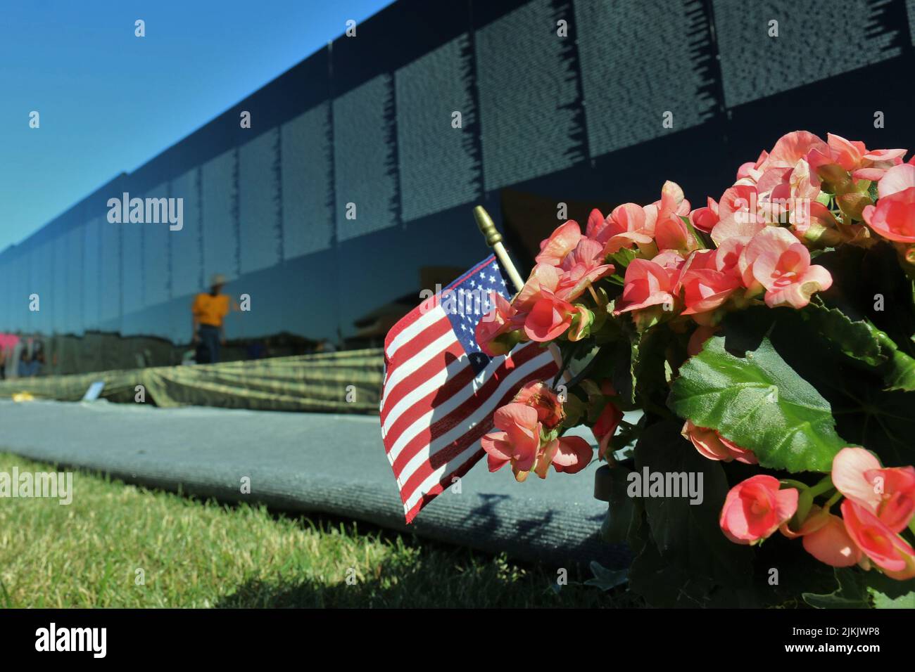 Un primo piano di fiori rosa e la bandiera americana contro il Vietnam Veterans Memorial Wall a Medina, Ohio Foto Stock