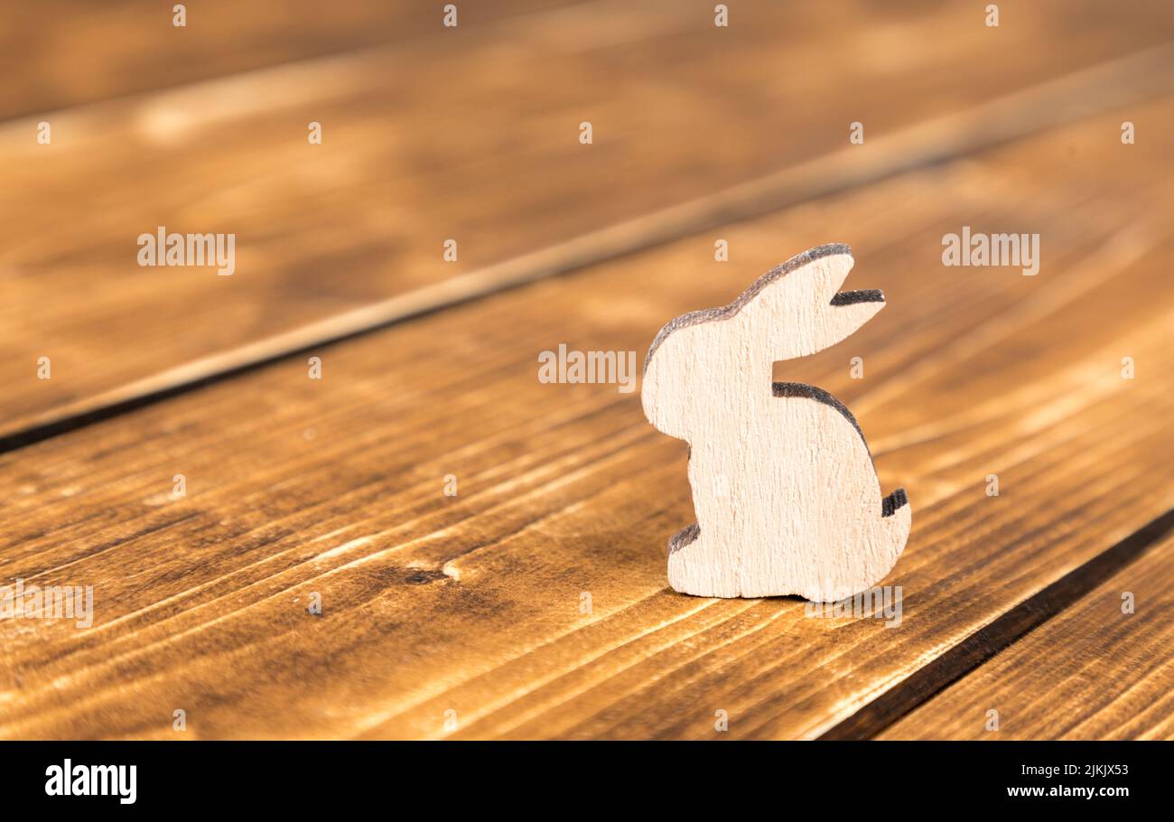 Uno sfondo pasquale con una forma di coniglietto di legno sul tavolo di legno Foto Stock