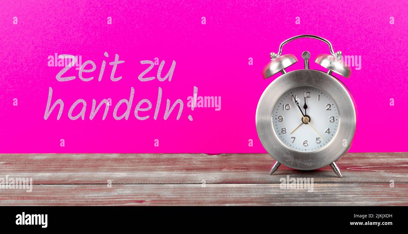 sveglia con sfondo rosa con testo tedesco zeit zu handeln, in inglese tempo di agire Foto Stock