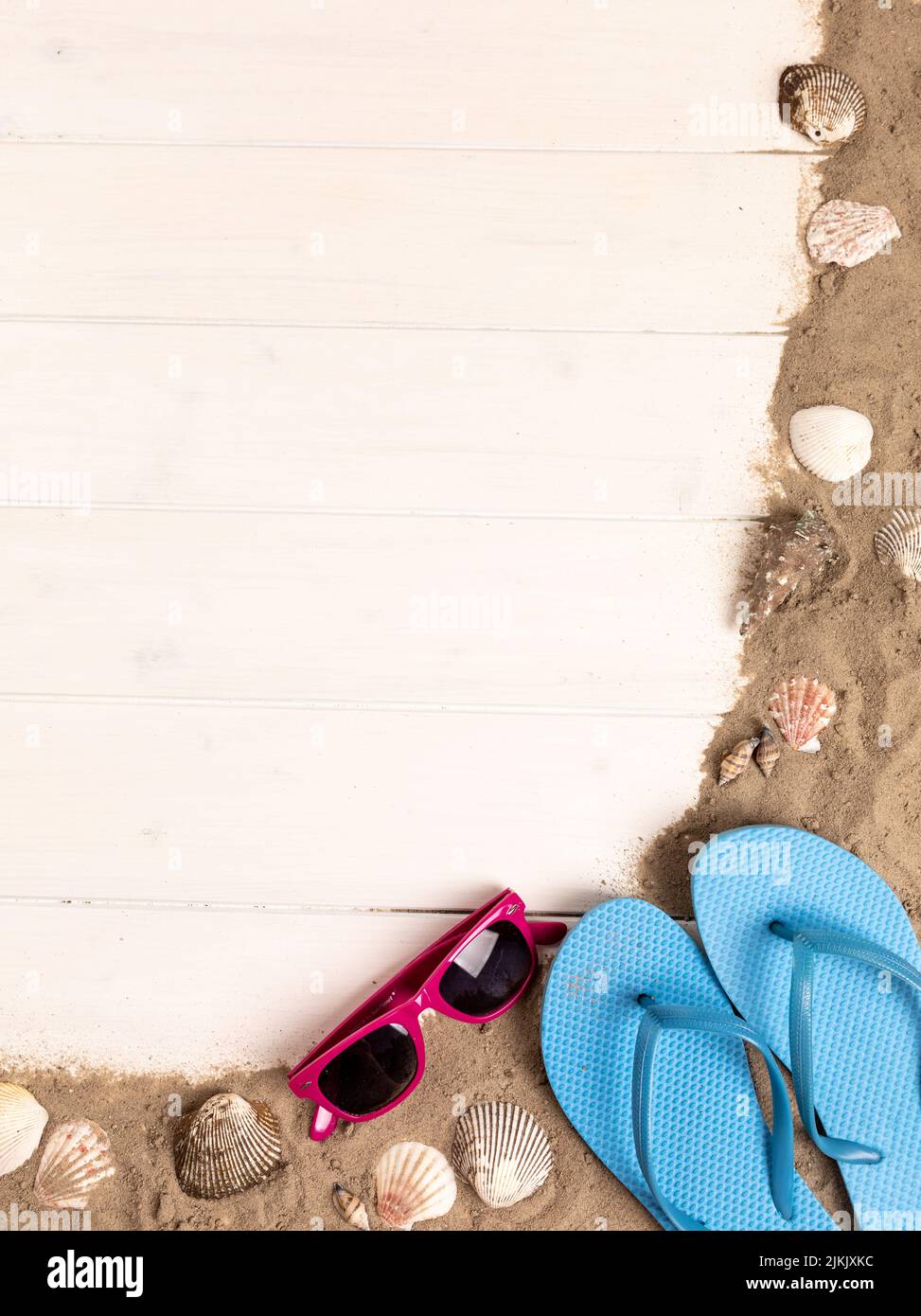 cornice con occhiali da sole, sabbia, molluschi e infradito su sfondo bianco di legno Foto Stock