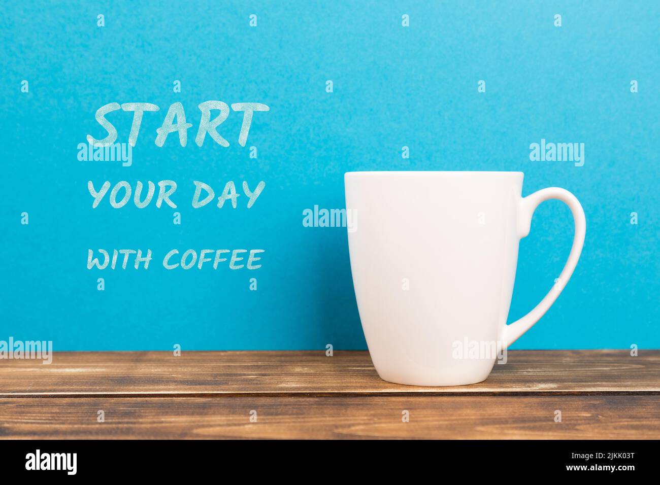 Un primo piano di una tazza bianca con il testo "inizia la giornata con il caffè" su sfondo blu Foto Stock