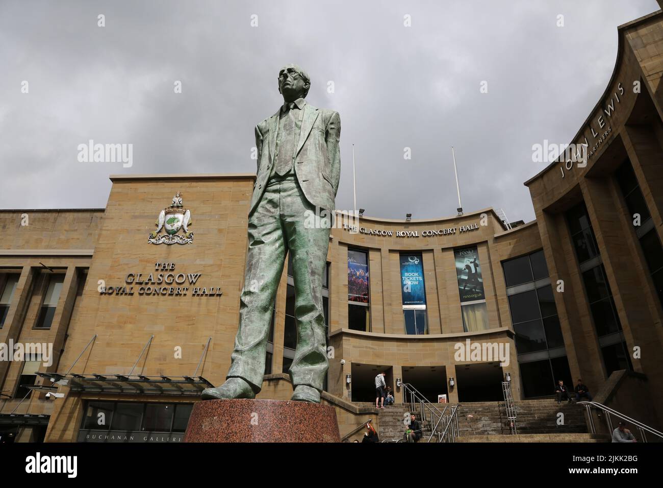 Glasgow, Scozia, Regno Unito. Statua di Scotlands primo ministro Donald Dewar fuori Royal Concert Hall.Glasgow, Buchanan Street.Statua di Donald Dewar in piedi all'estremità nord di Buchanan Street. Donald Dewar era un politico scozzese. In qualità di membro del Partito laburista, rappresentò la Scozia nel Parlamento britannico nel 1966-1970 e poi ancora dal 1978. Fino alla sua morte nel 2000 fu il primo Ministro della Scozia. La sua statua in bronzo si affaccia su Buchanan Street, una delle vie più belle della città, e si erge sui gradini della Royal Concert Hall. La statua fu svelata il 7 maggio 2002. Foto Stock