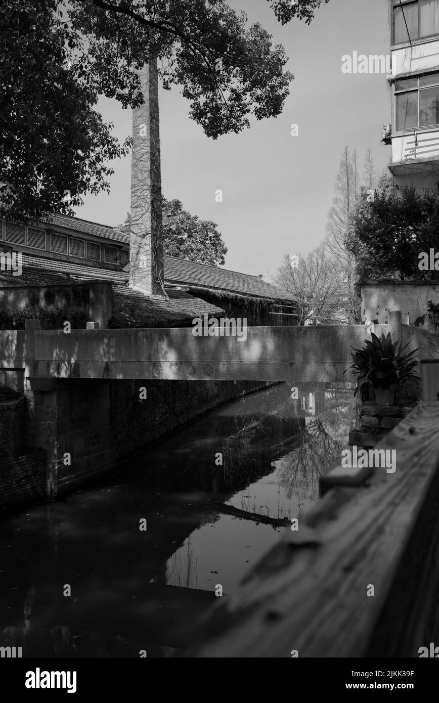 Un colpo in scala di grigi di edifici e ponte sul fiume nel vecchio villaggio. Shanghai, Cina Foto Stock