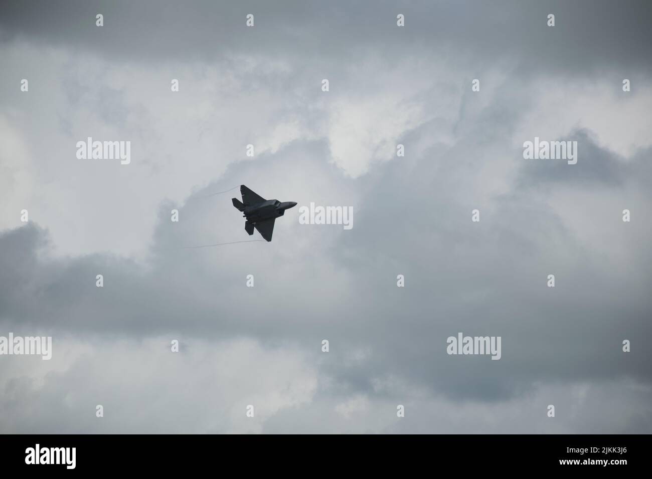 Un tiro a basso angolo di un velivolo furtivo Lockheed Martin F-22 Raptor che vola su cielo nuvoloso Foto Stock