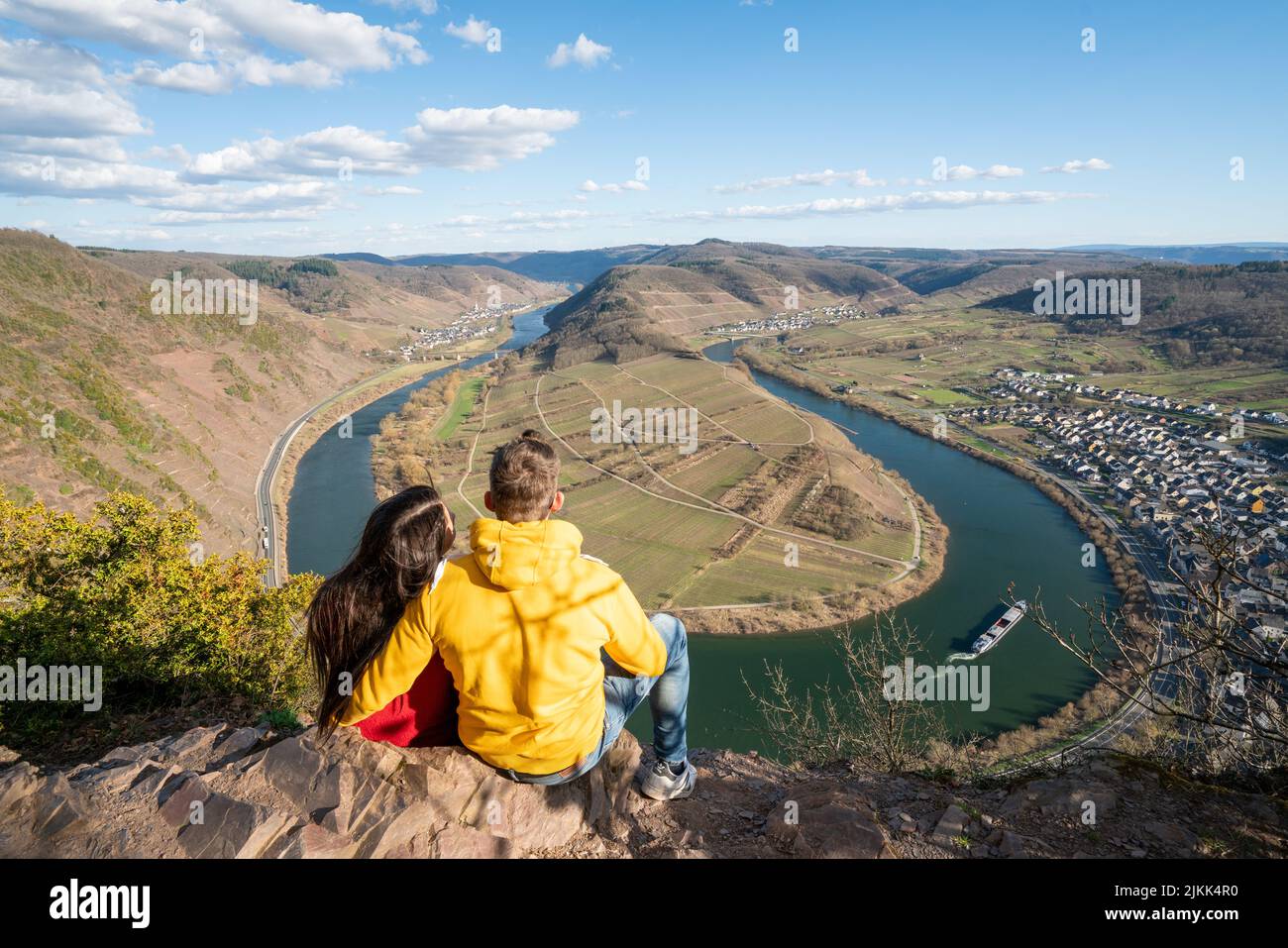 Un'immagine ad angolo alto di una giovane coppia seduta sul bordo della gola godendo dell'affascinante vista del lago e delle montagne Foto Stock