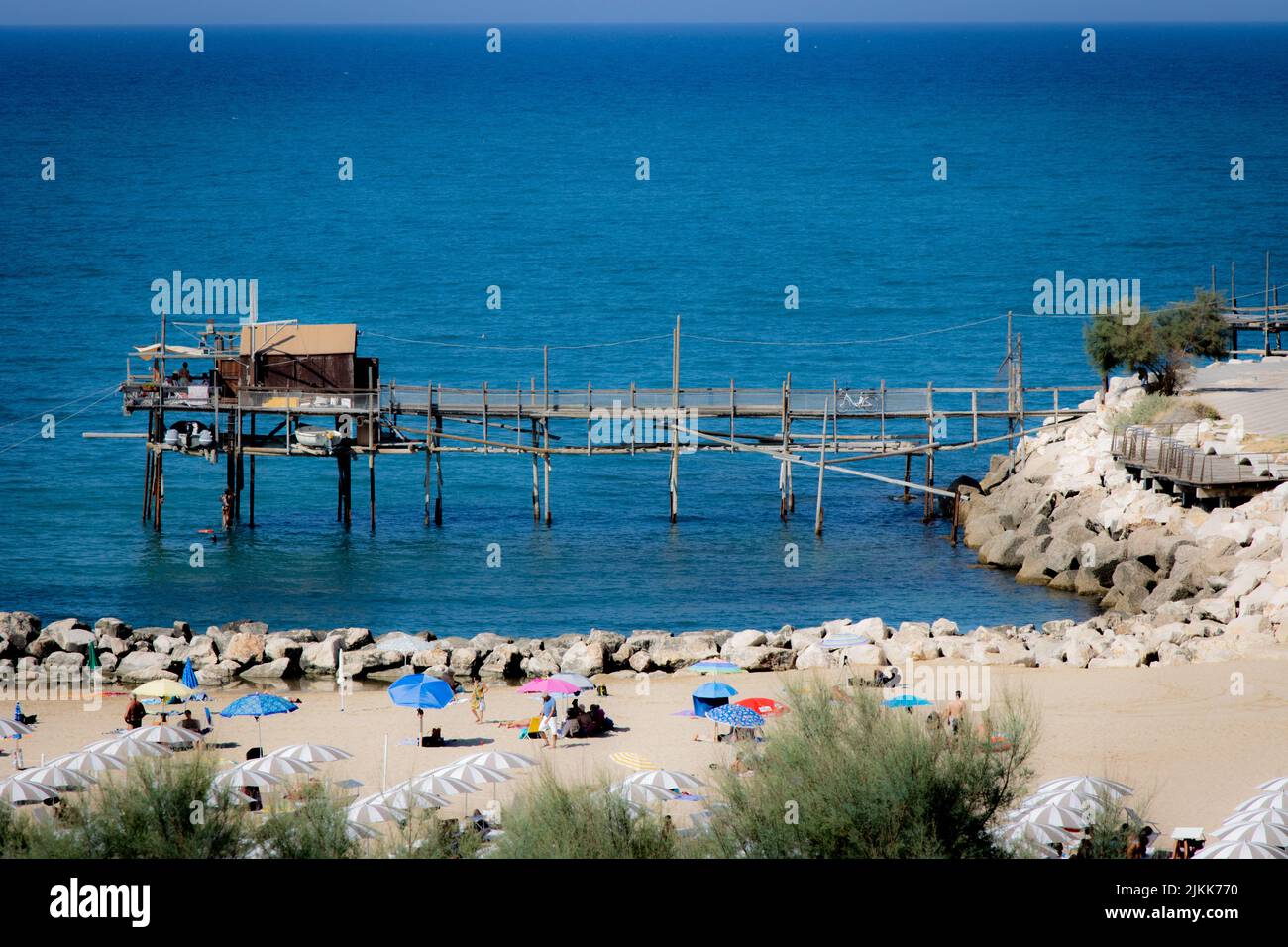 Una vista ad angolo alto di un molo e della spiaggia con gente e ombrelloni colorati Foto Stock