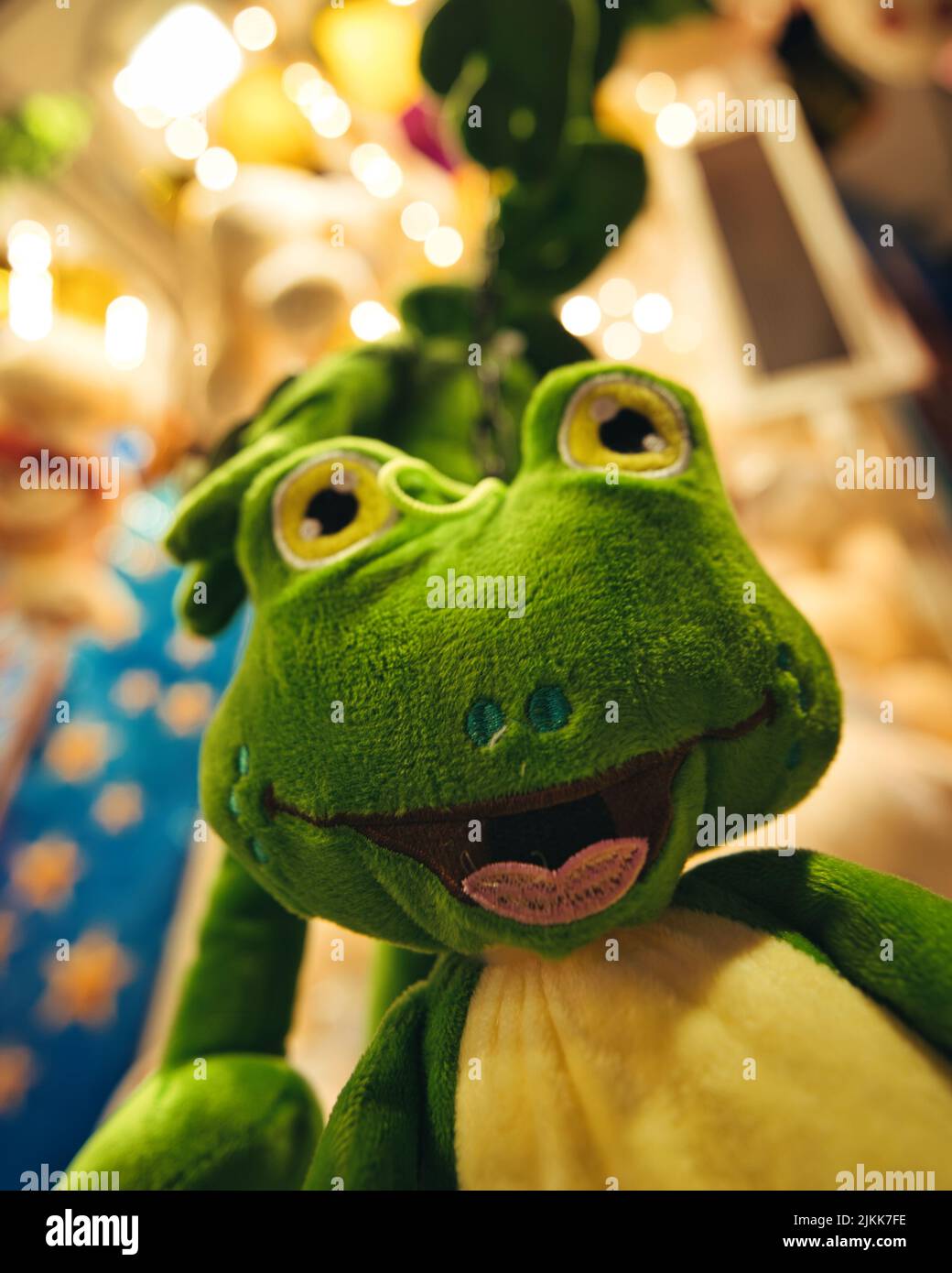 Una messa a fuoco morbida di un giocattolo di rana verde imbottito contro un terreno di gioco luminoso Foto Stock