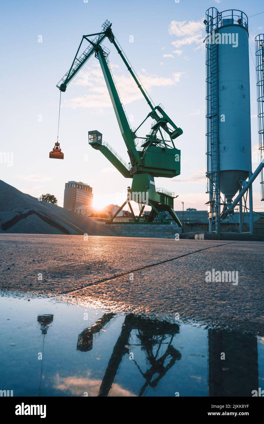 Il riflesso di una gru su una pozza d'acqua in un impianto industriale Foto Stock