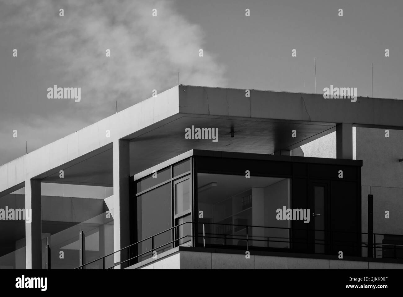 Un'immagine in scala di grigi di un moderno edificio di design sotto un cielo nuvoloso Foto Stock