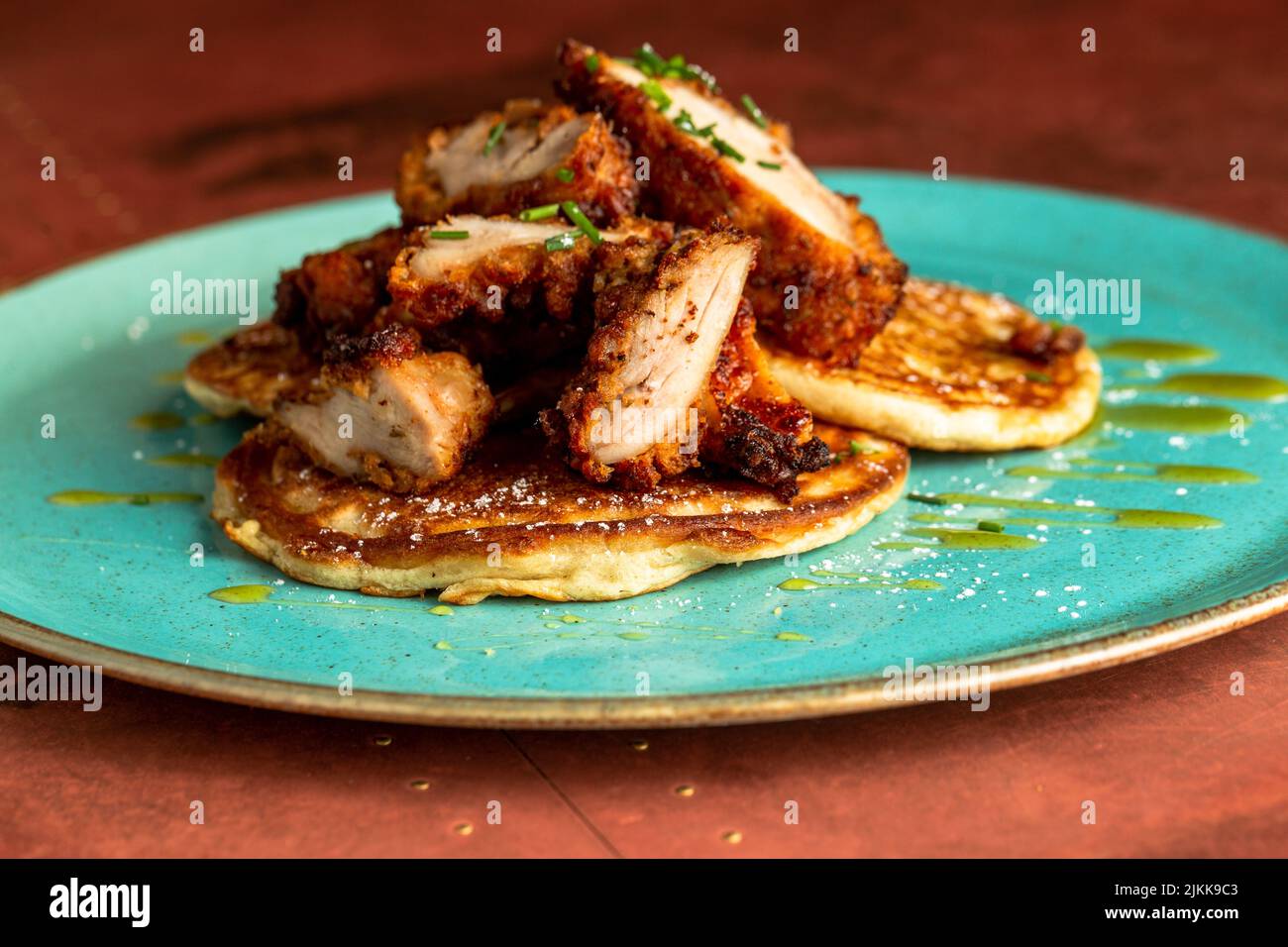 Un primo piano di una frittella con fette di pollo croccanti fritte sulla parte superiore Foto Stock