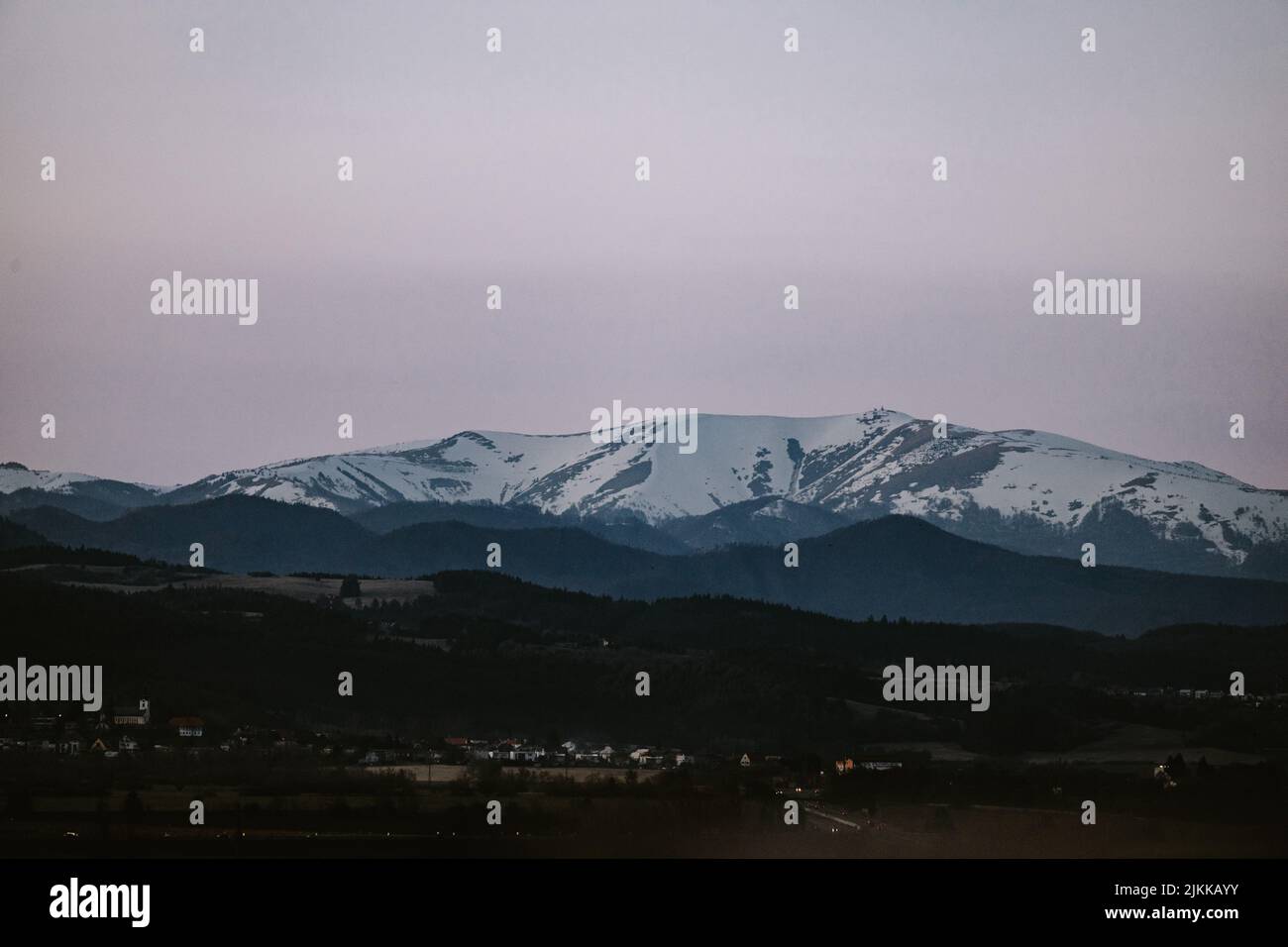La vista della cima parzialmente innevata di Krnzna dalla città di Zvolen in Slovacchia durante l'ora blu Foto Stock
