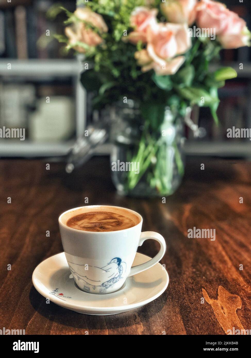 Uno shot verticale di una tazza di caffè in una tazza estetica sul tavolo di legno a Pechino Foto Stock