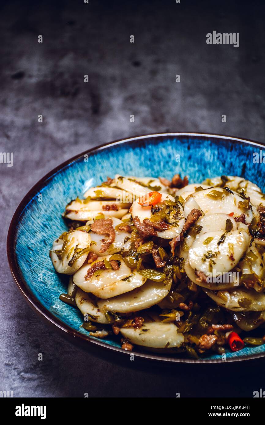 Un colpo verticale di una porzione di torta di riso fritto con maiale grattugiato e verdure salate su un piatto blu Foto Stock