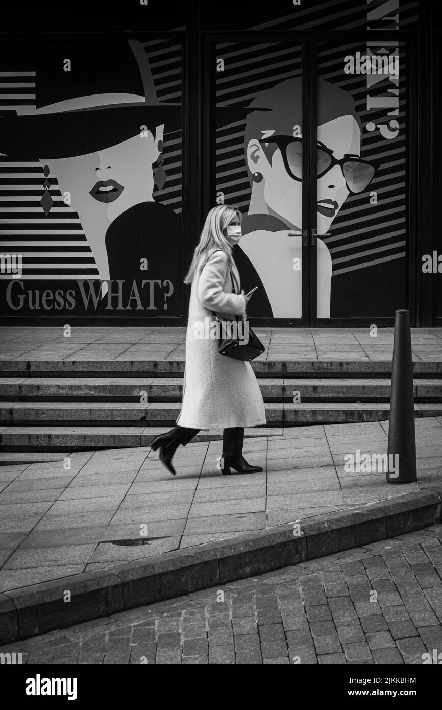 Una foto in scala di grigi di una donna che passa per la via Nishantashi a Istanbul con un muro artistico sullo sfondo Foto Stock