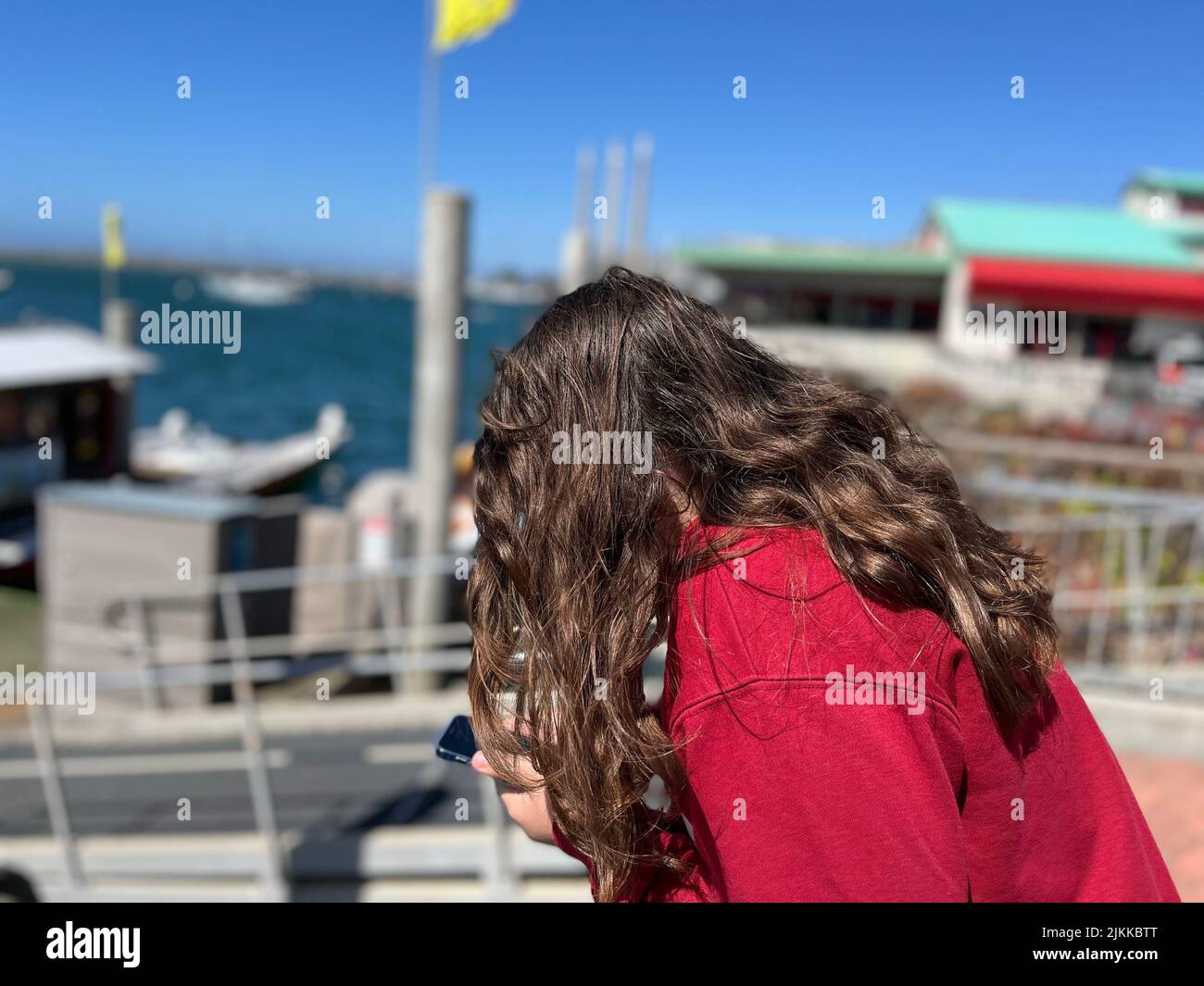 Una giovane ragazza con capelli ricci che si affaccia sulla baia dalle banchine in California Foto Stock