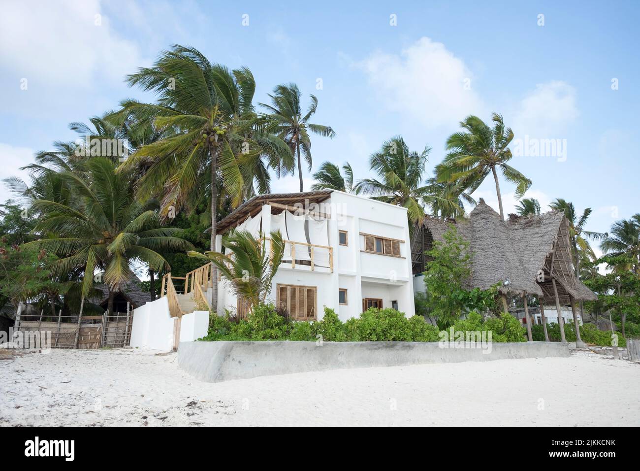 Alte palme che circondano una casa bianca sulla spiaggia di Zanzibar, Tanzania Foto Stock