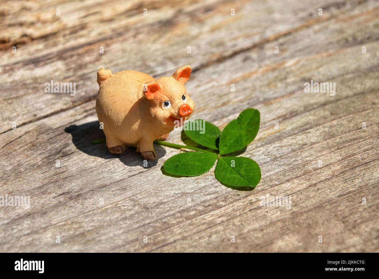 Una figura di maiale piccola con le foglie su una superficie di legno Foto Stock