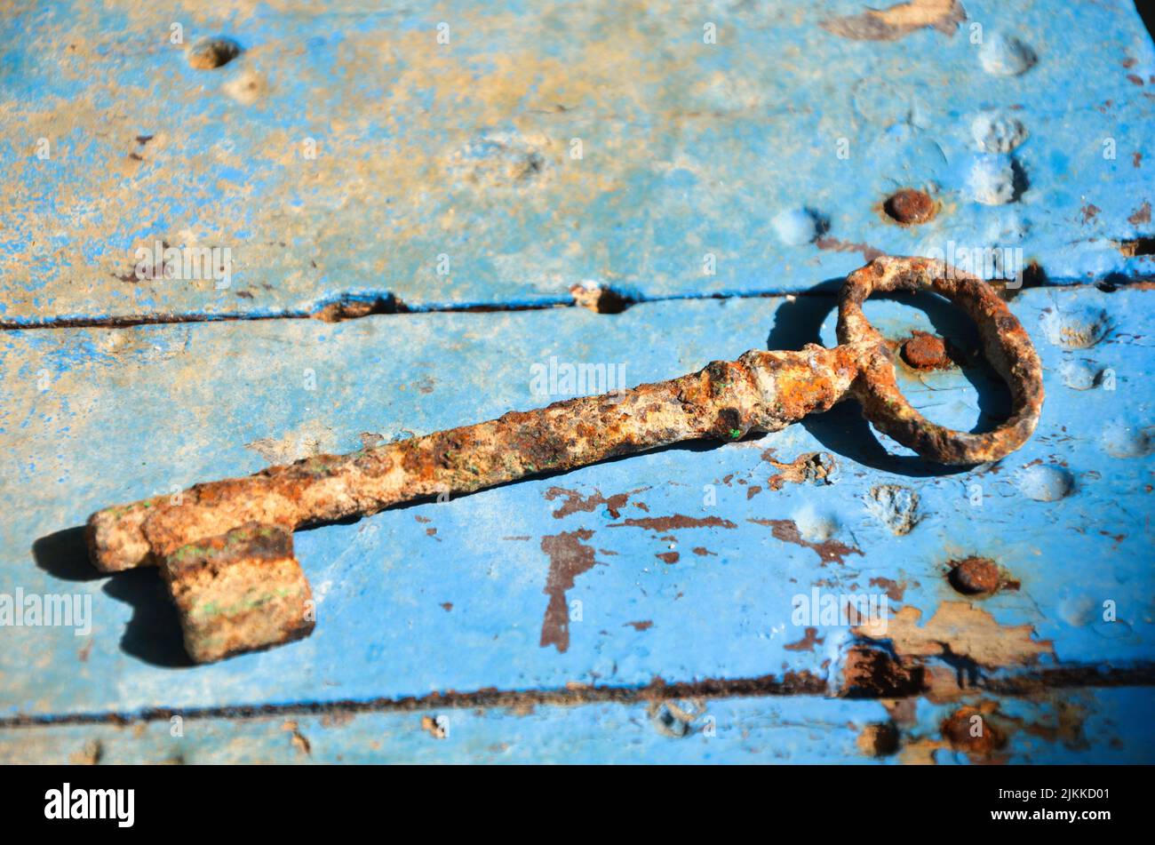 Una vecchia chiave arrugginita su una superficie di legno blu grungo Foto Stock