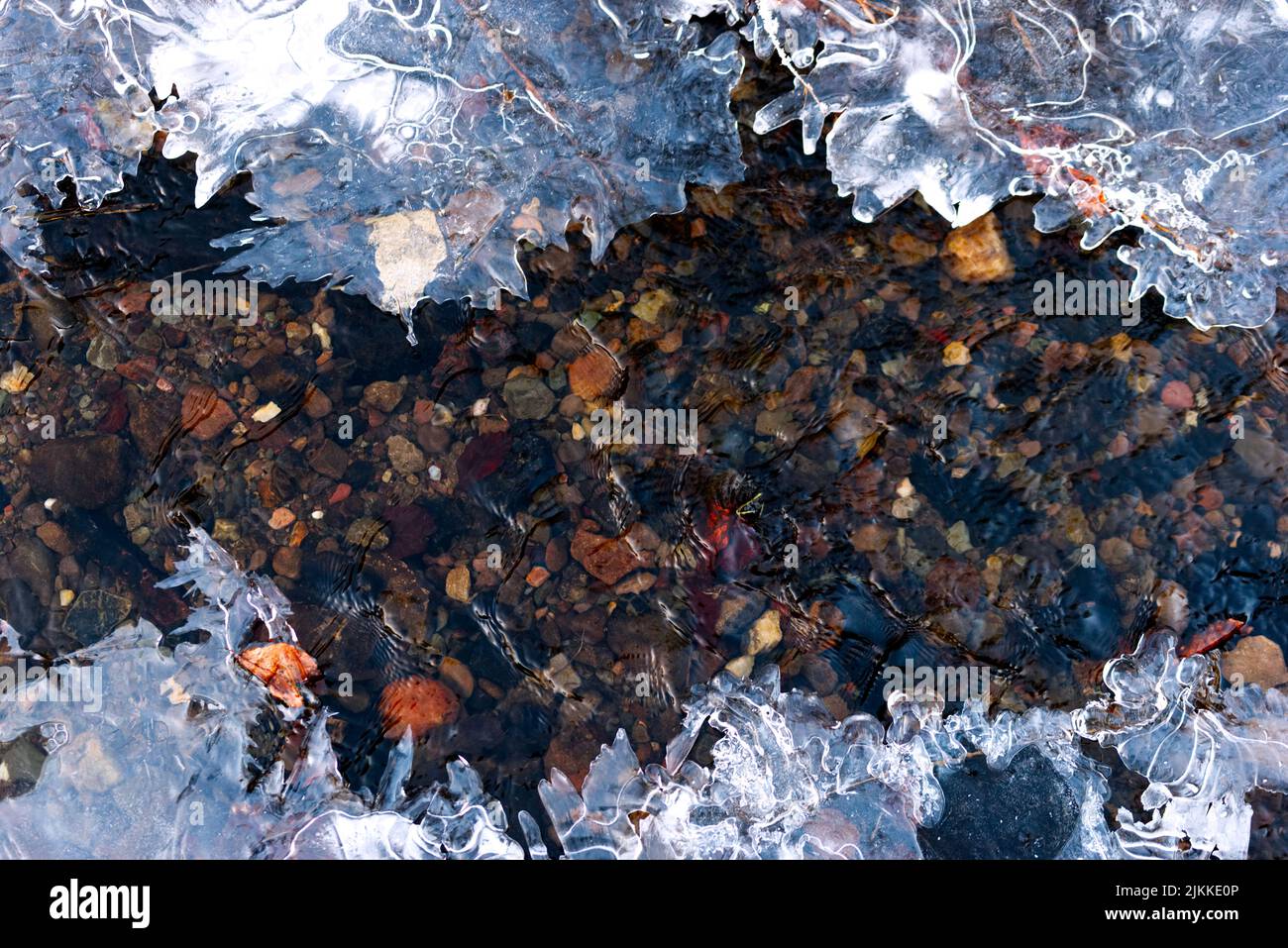 Il ghiaccio su un fiume ghiacciato con ciottoli sott'acqua Foto Stock