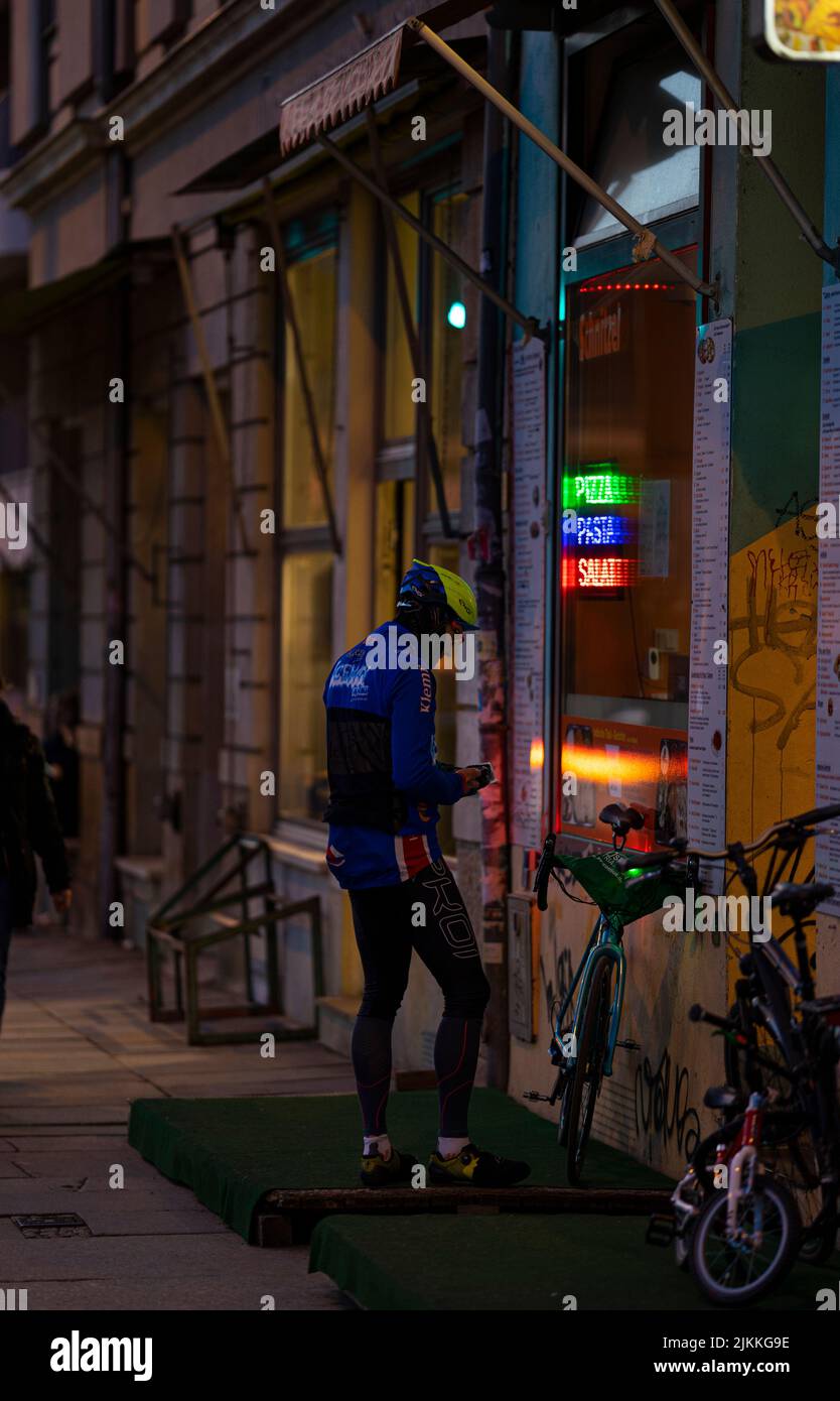 Un focus selettivo di un ciclista che ordina la pizza durante la serata in città Foto Stock