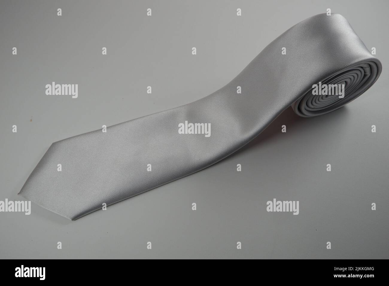 Un primo piano di un rotolo grigio di cravatta in raso maschio isolato su sfondo bianco Foto Stock