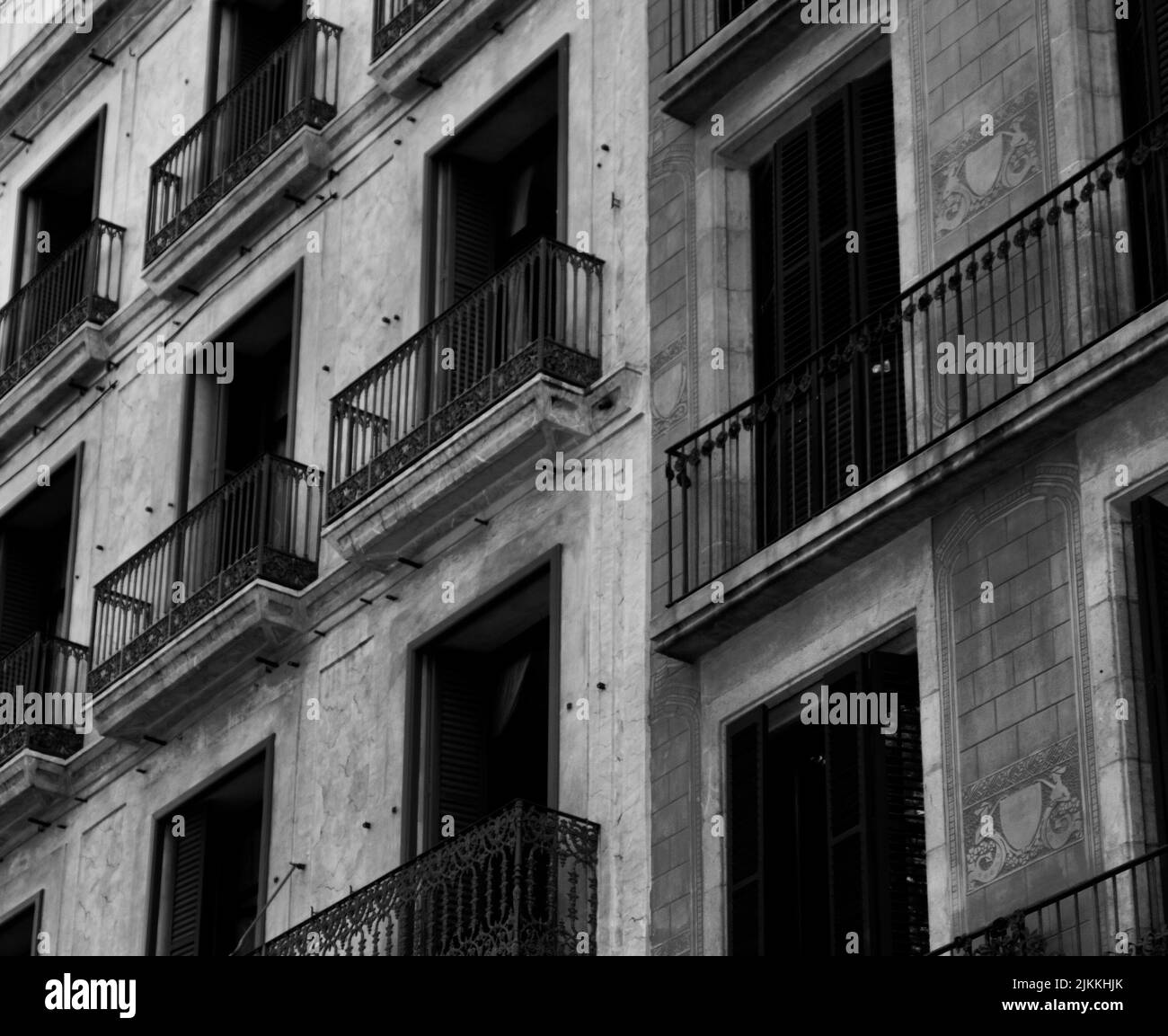 Un'immagine in bianco e nero di un vecchio edificio europeo di appartamenti nel centro della città con piccoli balconi Foto Stock
