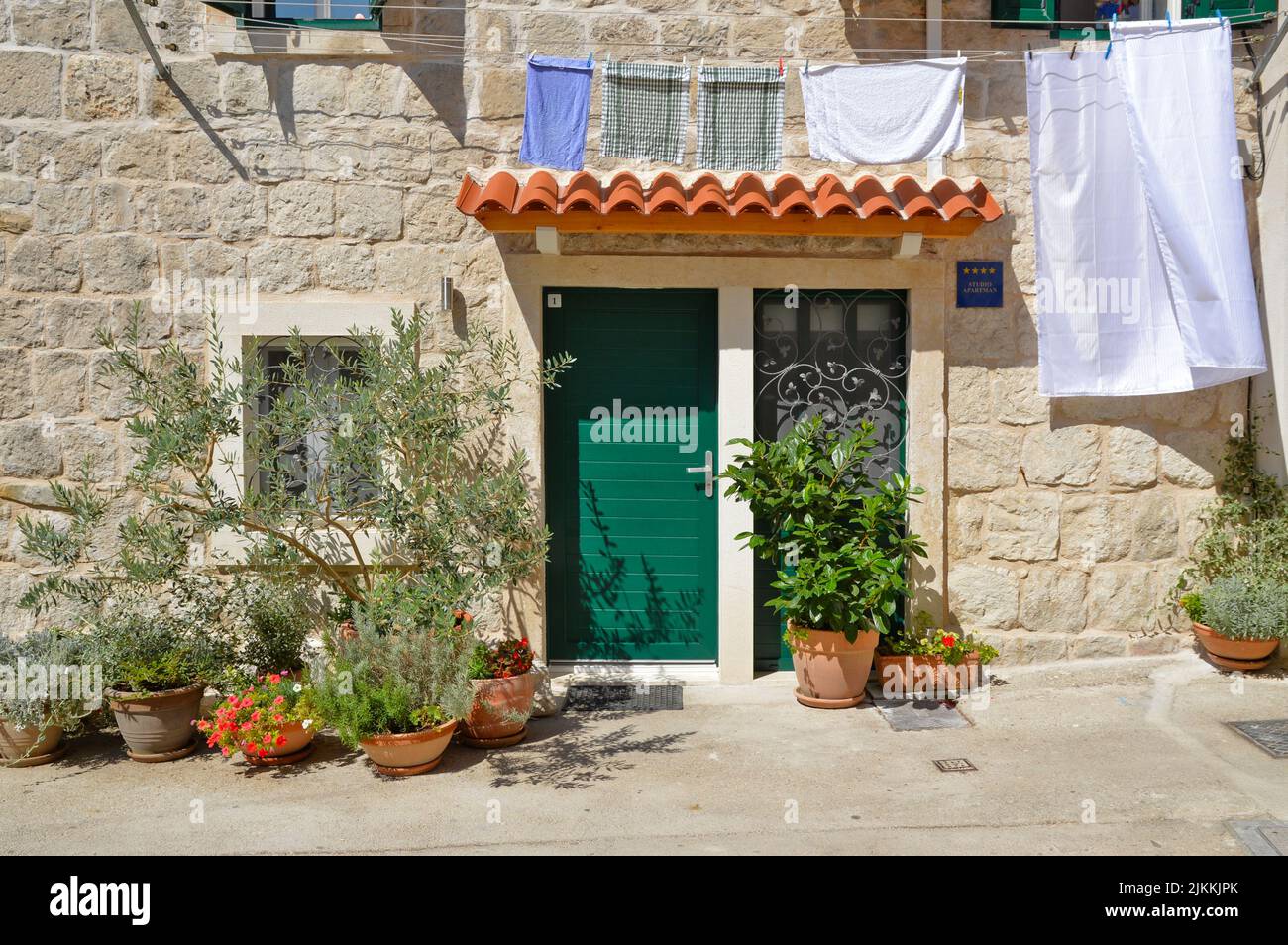 Una casa carina con una porta verde decorata con piante e lavanderia appeso a una corda a Spalato, Croazia Foto Stock
