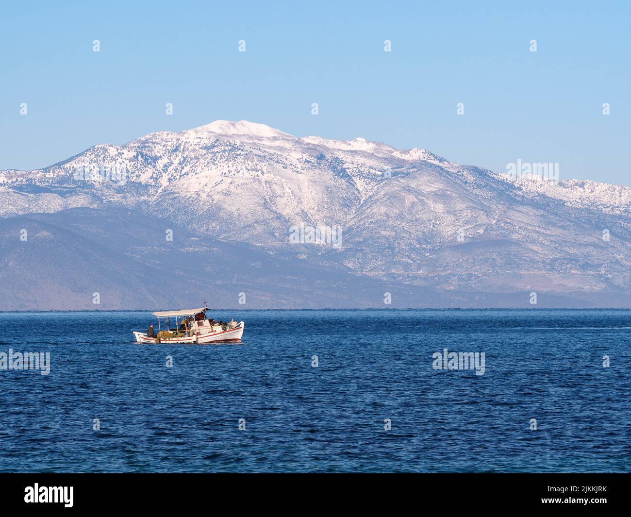 Una vista panoramica di una barca a vela in mare aperto contro una montagna innevata nel golfo di Corinthia a Kiato, Grecia Foto Stock