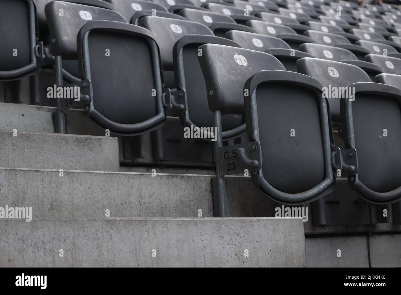 Le file vuote di sedie nere di uno stadio, isolate su uno sfondo sfocato Foto Stock