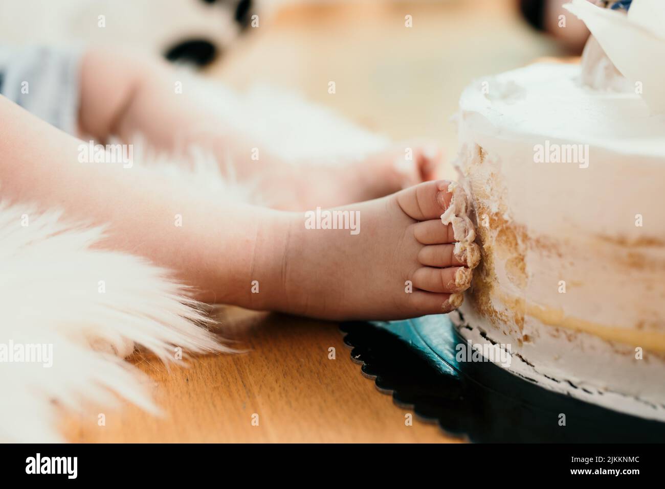 Un primo piano di un bambino cute toes che dissuica una torta bianca Foto Stock