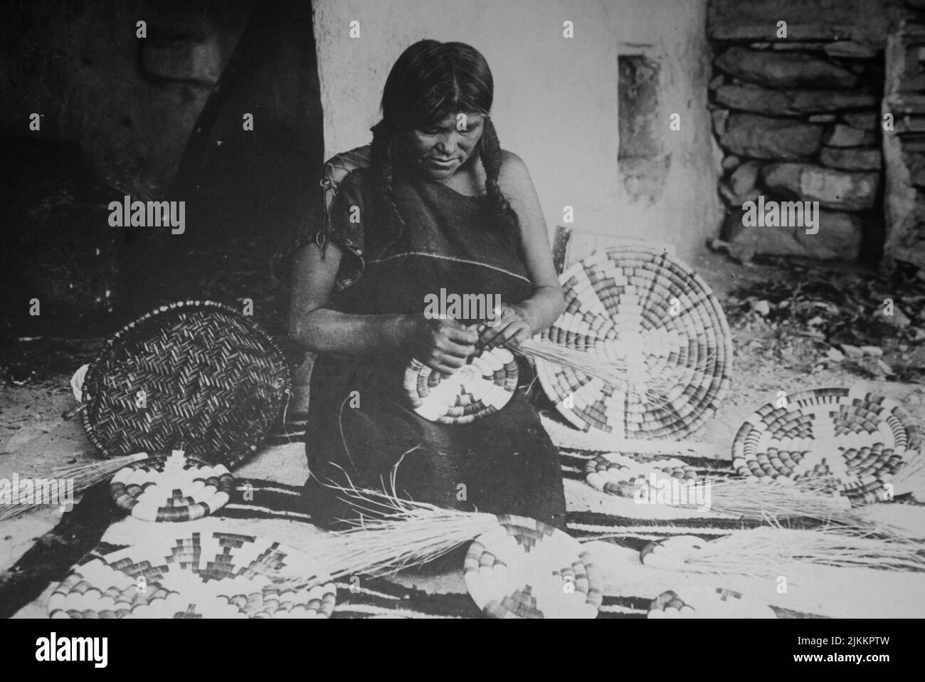 Fotografia storica in bianco e nero di una donna Hopi Pueblo che tesse tradizionali vassoi di cestini Foto Stock