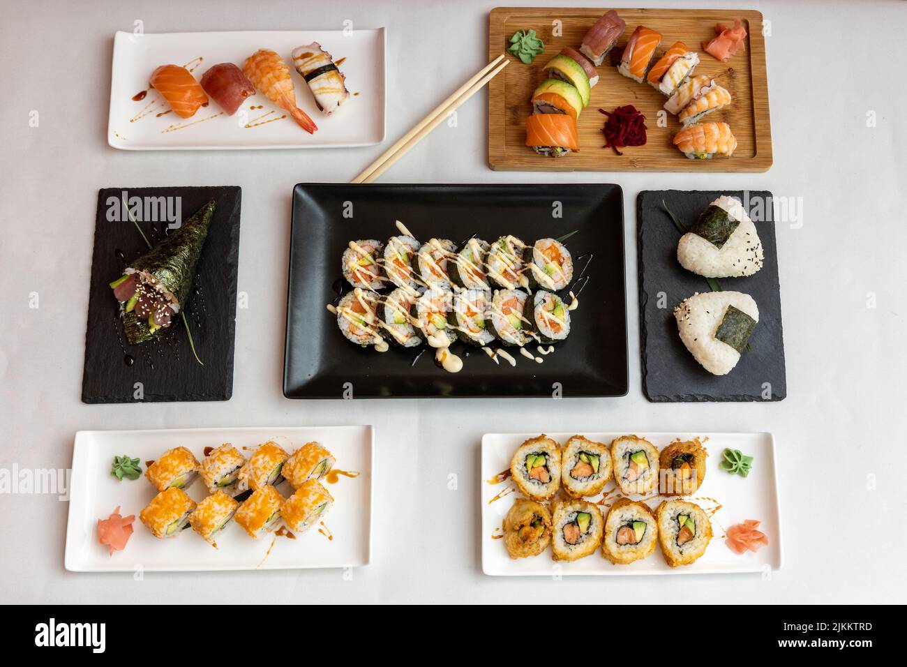 Una vista dall'alto di diversi tipi di sushi sui piatti su uno sfondo bianco Foto Stock