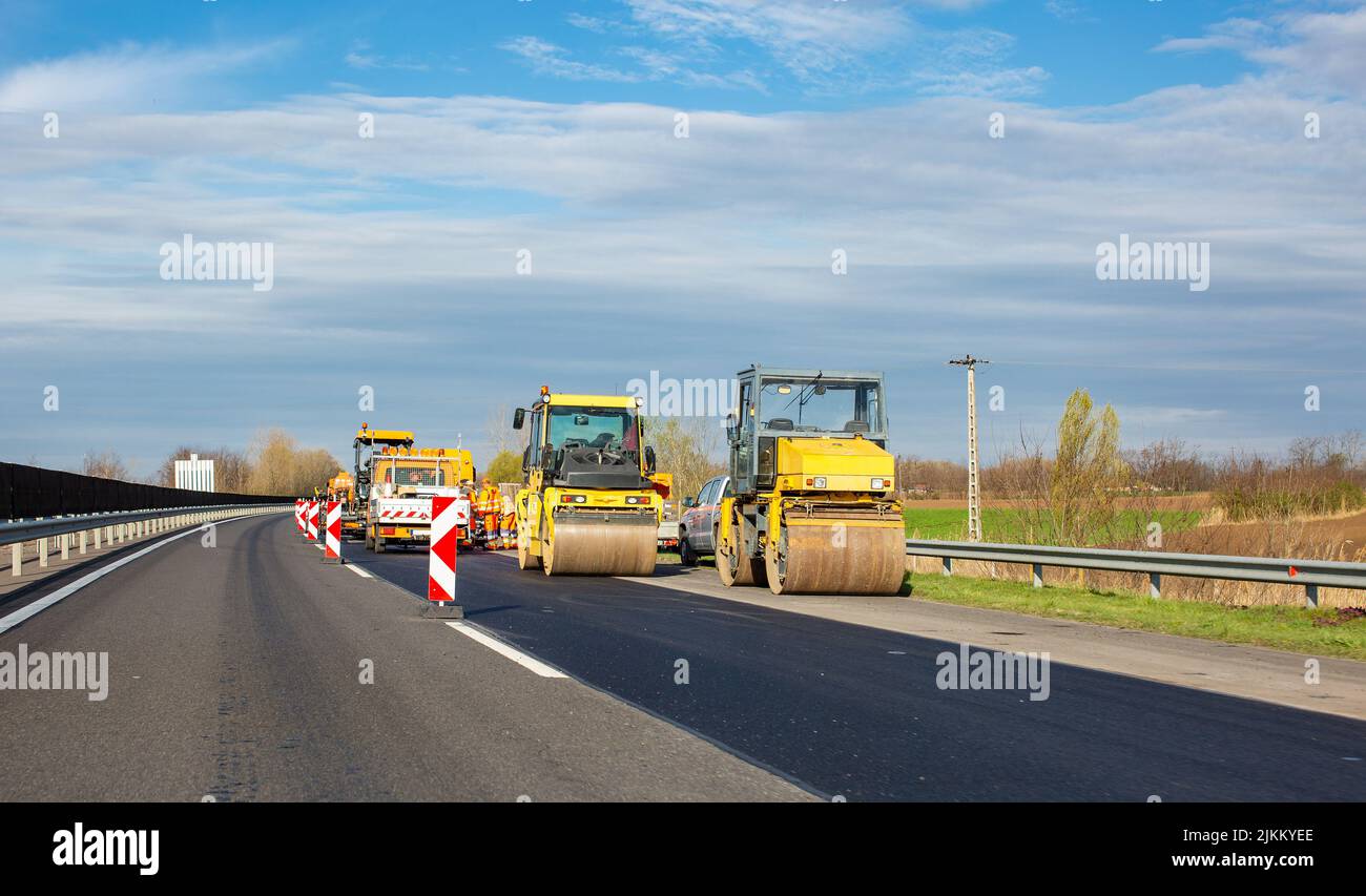 La strada lavora in autostrada. Rulli per asfalto e altre attrezzature Foto Stock